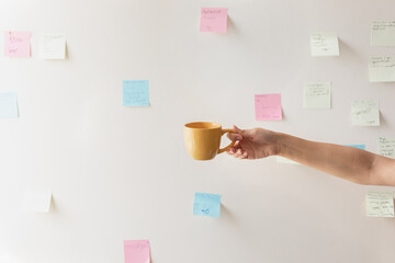 hand with a mug on the background of the wall