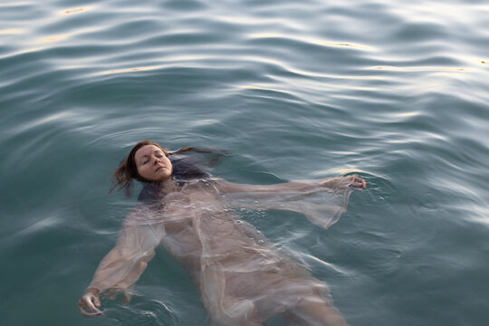 mindfulness, woman floating in water with closed eyes in nature