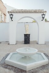 Attractive white stone fountain with black pebbles at the base
