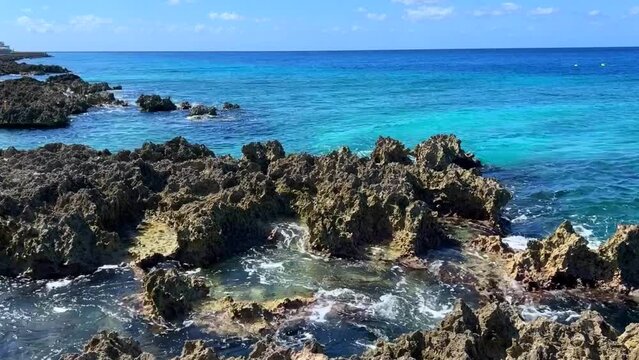 Waves crashing on the shore at Turtle Reef in Cayman Islands on a sunny day.