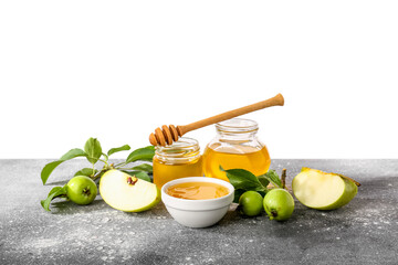 Jars with sweet honey and green apples on table against white background