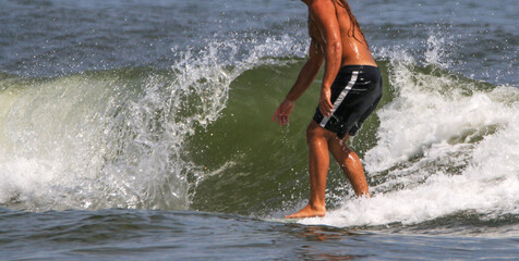 Man with no shirt surfing in the ocean next to a wave curling