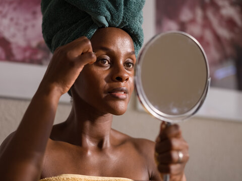 Black woman plucking eyebrows during beauty routine