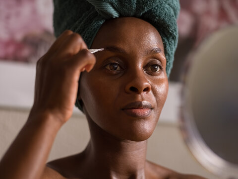 Woman plucking eyebrows after bath