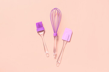 Pastry brush, whisk and spatula on pink background