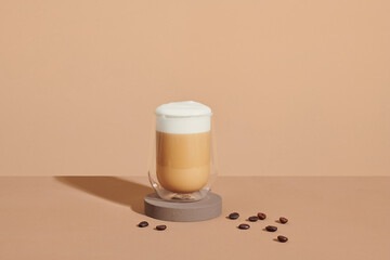 Cappuccino in a double walled glass with roasted coffee beans.