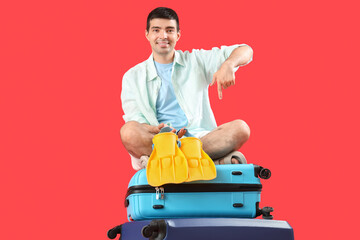 Male tourist with suitcases and paddles on red background