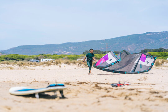 Male surfer preparing kite on beach