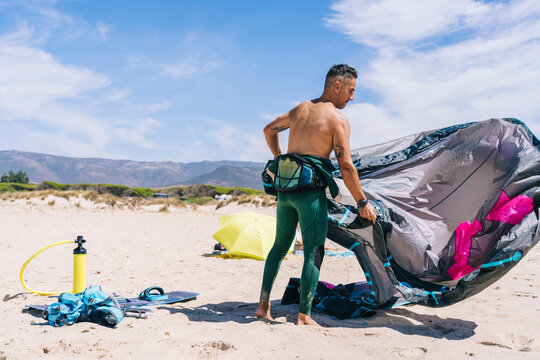 Sportsman preparing kite surfing equipment on sea shore
