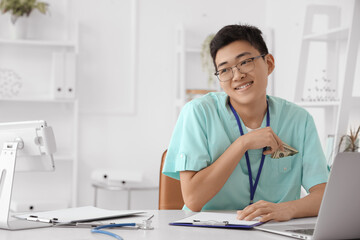 Fototapeta premium Male Asian doctor with bribe in clinic