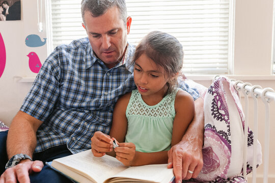 Girl reading at home with her father