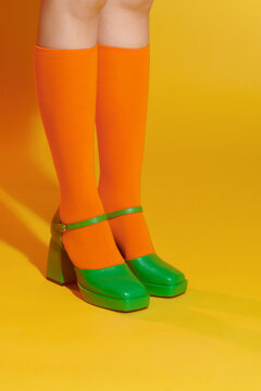Female legs in colorful socks and green heeled shoes
