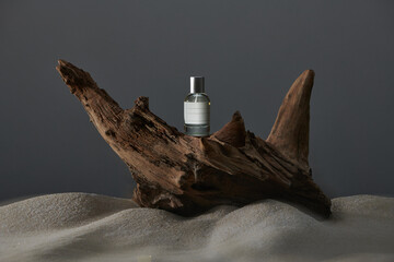 Perfume bottle with a label on tree bark on a dark background