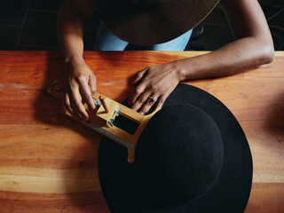  Close-up of hands and hat. woman hat maker in a workshop space. 