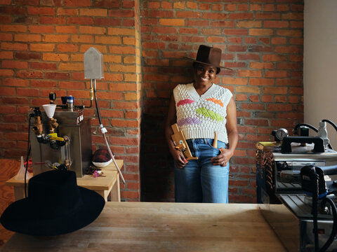  Black woman hat maker in a workshop space. 