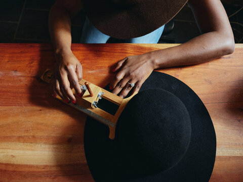  Close-up of hands and hat. woman hat maker in a workshop space.  - Powered by Adobe