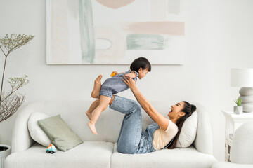 young woman throwing up her daughter playing at home