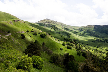 Fototapeta premium Landscape of Trialeti (Caucasus) mountain range with Tskhratskaro Pass, Georgia, gravel dangerous M-20 road and vibrant green grasslands in summer.