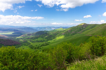 Landscape of Trialeti (Caucasus) mountain range seen from M-20 road to Tskhratskaro Pass, lush green mountains and grasslands, Bakuriani ski resort in summer, Georgia.