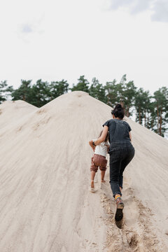 Woman and Her Toddler Daughter Ascend a Towering Sand Pile