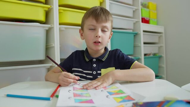 The boy concentrates on the tasks given by the teacher. Dissatisfied that he has to do an exercise he doesn't like. High quality 4k footage