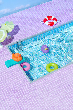 Orange rubber ducky on diving board of swimming pool.