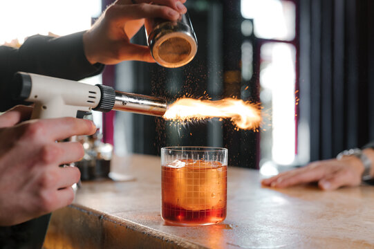 Barman adding cinnamon in alcohol cocktail