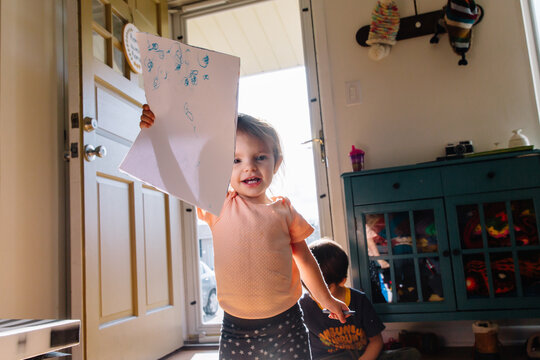 Toddler proudly holds up her writing scribbles