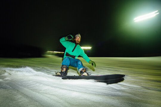 A snowboarder maneuvers in the snow