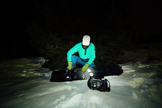 An athlete gets his snowboard ready