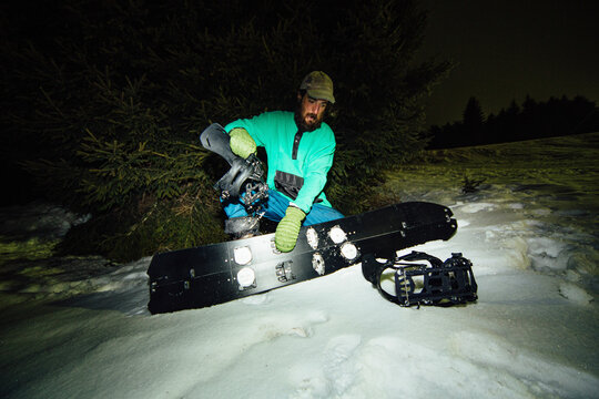 An athlete prepares his snowboard