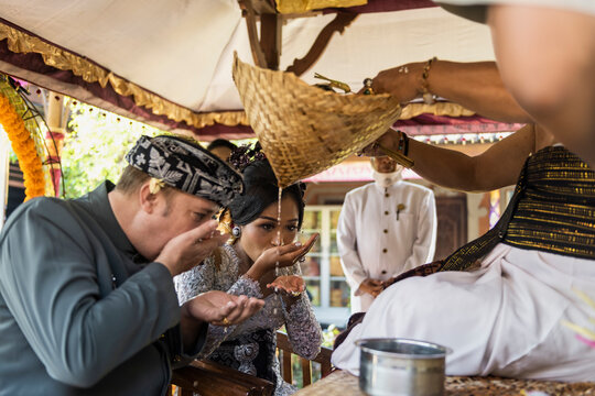 Balinese bride and caucasian groom during multiracial wedding ceremony