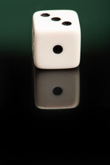 Dice, classic dice resting on reflective surface, selective focus.