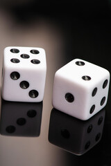 Dice, classic dice resting on reflective surface, selective focus.