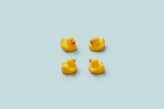 Four yellow rubber duckies on plain background.