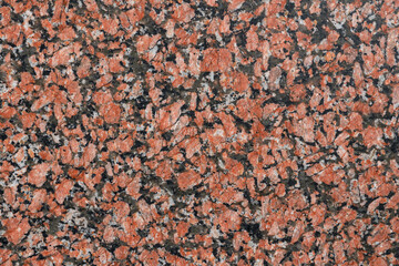 Red, black, gray spotted granite. Interesting background or texture. Material for decoration interior or exterior design. Natural stone.
