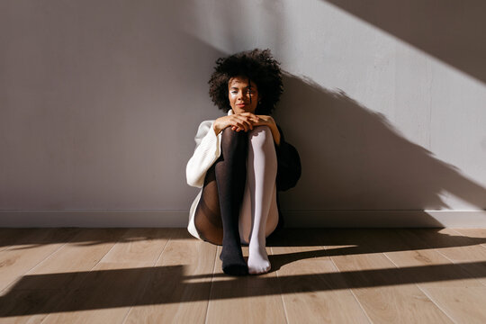 Black model sitting against wall with shadow
