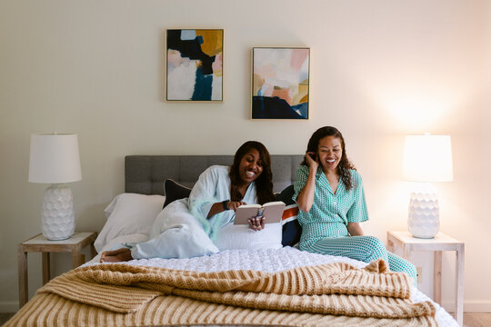 Girl friends reading together in bedroom