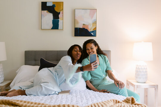 Women couple using phone in bed