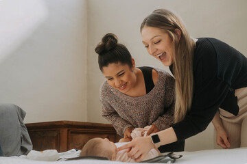 Two mothers changing their newborn's diaper for the first time
