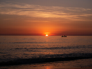 Sunset in Italy Toskana at mittelmeer with fishing boat in the water and small Waves Dawn