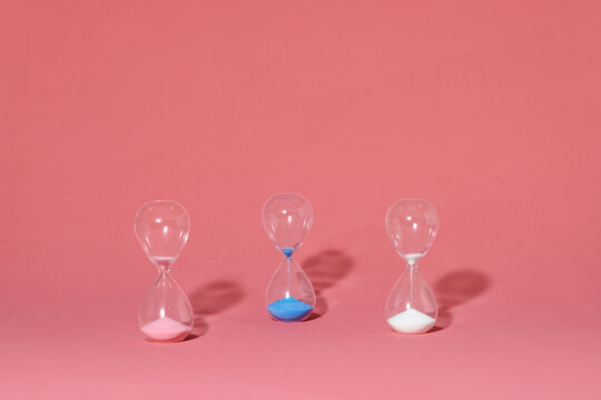 three hourglasses discharging into the container below