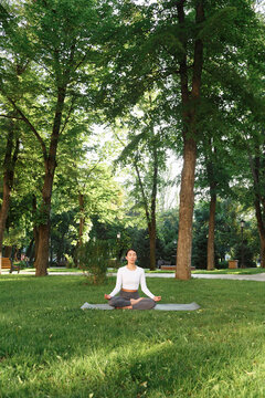 Lady gesticulating Gyan mudra in Padmasana on lawn