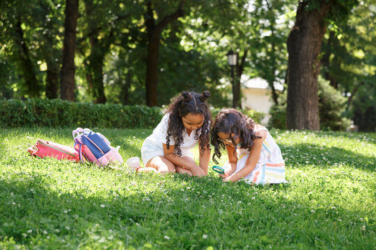 Curious girls exploring nature using magnifying glass