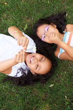 Laughing multiracial girlfriends lying on grass
