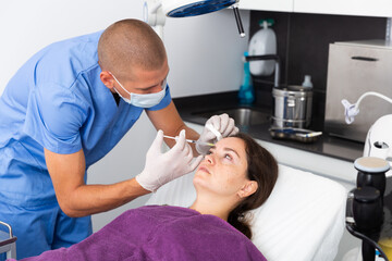 Young woman getting procedure of injection contouring for facial correction in aesthetic cosmetology clinic