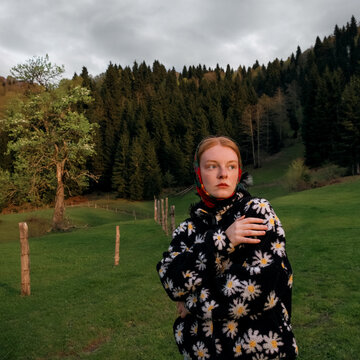 A close portrait of a red haired girl in the mountains 