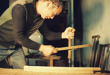 The carpenter is using tools to drill holes