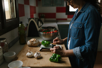 Woman is weighing peppers in the kitchen