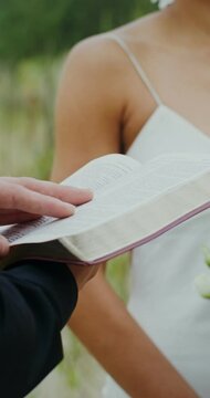 Close-up of the bible in the priest's hands during an outdoor wedding